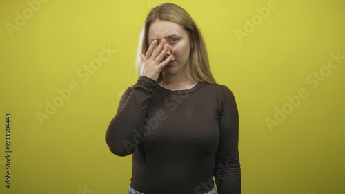 Woman presses hand to forehead in studio in a visible facepalm gesture and tense expression; embarrassment regret.
