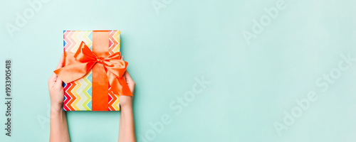 Wallpaper Mural Woman hands give wrapped christmas or other holiday handmade present in colored paper. Present box, decoration of gift on Blue table, top view with copy space Torontodigital.ca