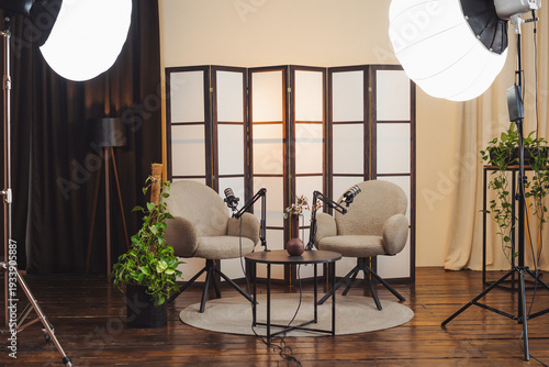 Podcast setup with microphones and seating area for discussion in a studio space with plants