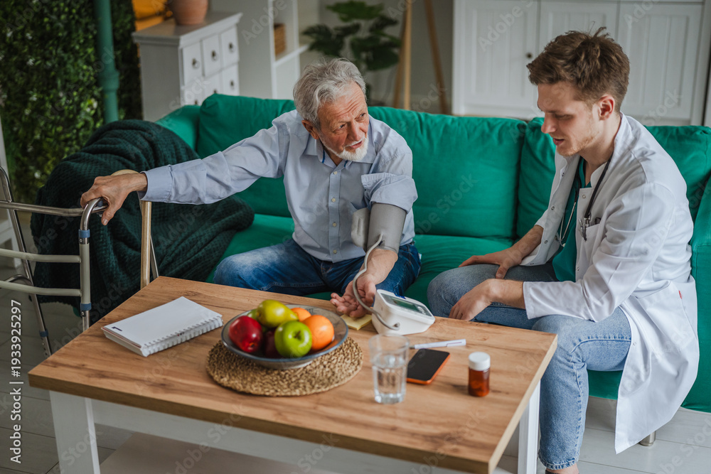 Fototapeta premium Doctor visiting senior male patient measuring blood pressure