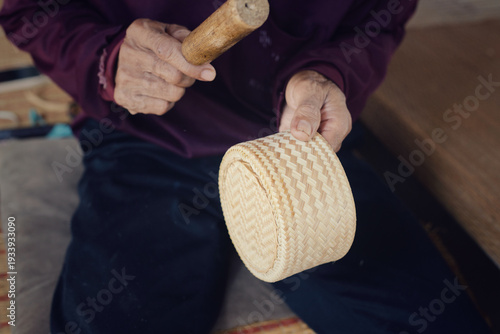 Artisan hands making traditional bamboo sticky rice container or Kratip Khao using wickerwork technique.