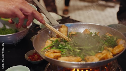 Chefs prepare traditional cha ca fish with turmeric and fresh herbs at Cha Ca Thang Long restaurant in Hanoi, Vietnam, showcasing a classic northern Vietnamese culinary experience.