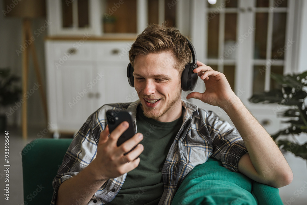 Fototapeta premium Young man enjoying music listening to headphones at home