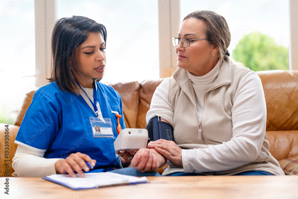 Fototapeta premium Nurse checks blood pressure of patient in a bright living room during daytime