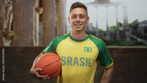Фотография Man in brasil jersey holding basketball with right hand and smiling at camera in studio; pride team spirit