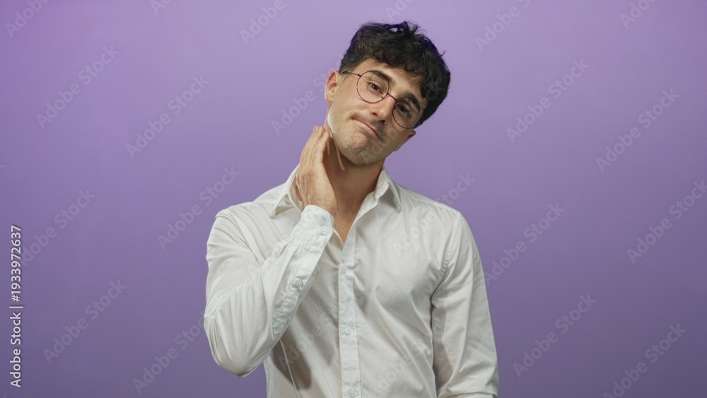 Fototapeta premium Young hispanic man in white shirt and round glasses with hand on neck and fingers touching throat in a purple studio; discomfort.
