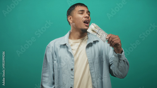 Foto Man holding fanned us dollar bills by his face in studio, gesturing and closing eyes in boastful display; confidence