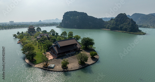 Canvastavla An aerial view of a beautiful Chua Vang  temple complex situated on an island in a tranquil lake, framed by dramatic karst mountains