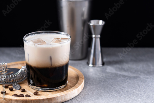 Refreshing Boozy White Russian Cocktail with Vodka and Cream on gray stone and black background. Copy space