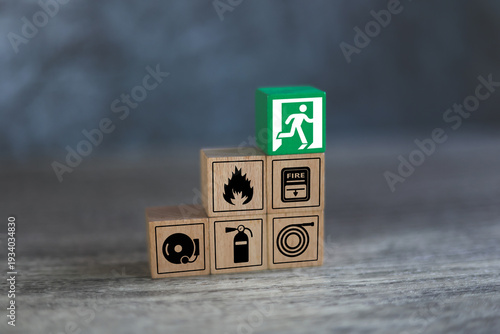 Hand choose cube wooden block stack with fire prevent icon and door exit sing or escape with fire extinguisher and emergency protection symbol for safety and rescue in the building.