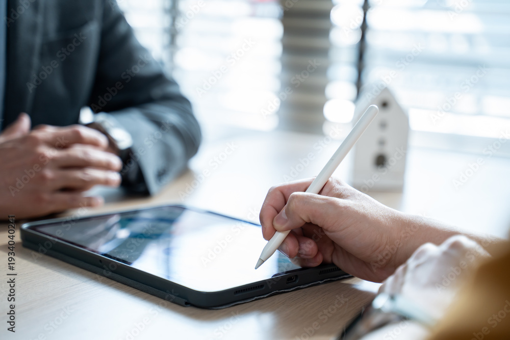 Obraz premium Close up of customer using a stylus pen to sign digital insurance contract on a tablet with an agent.Concept of home insurance deal,financial agreement success,partnership and mortgage loan approval