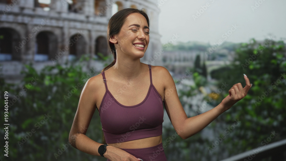Naklejka premium Woman playing air guitar and smiling by the roman coliseum on a building terrace balcony; vacation joy.