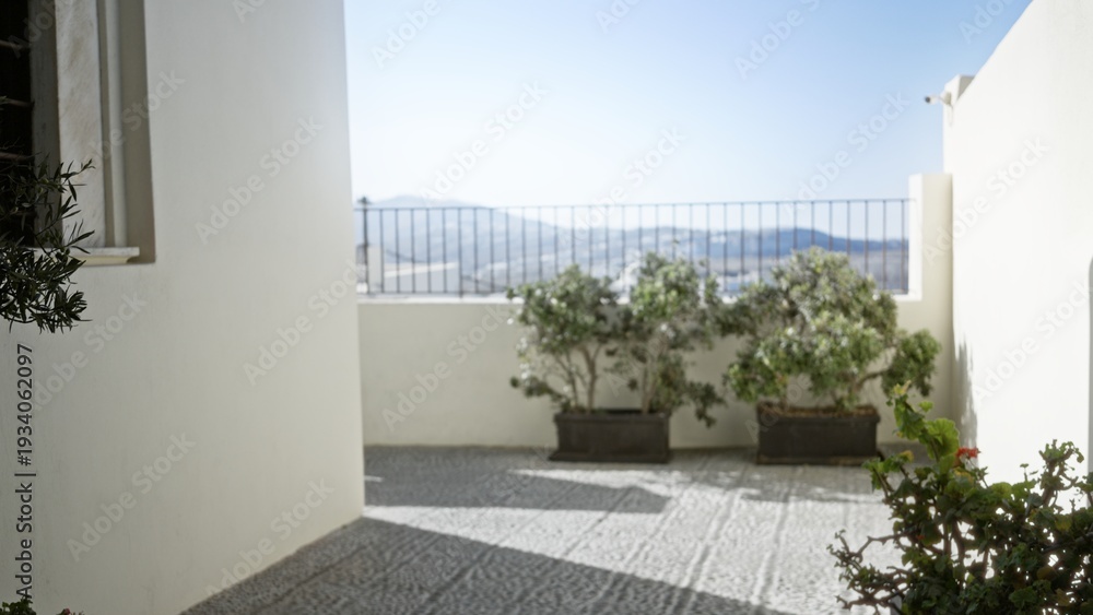 Fototapeta premium Sunlit terrace with potted shrubs, defocused railing and distant hills in soft bokeh outdoor; background copyspace backplate calm.