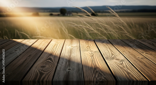 Rustic wooden table in golden hour sunlight, display foreground with shadows. Blurred natural field landscape creates serene outdoor ambiance