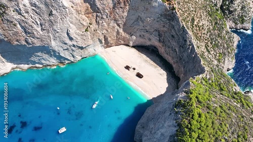 Aerial drone view of famous Navagio Shipwreck Beach with turquoise sea water and boats in Zakynthos island, Greece on a bright sunny da