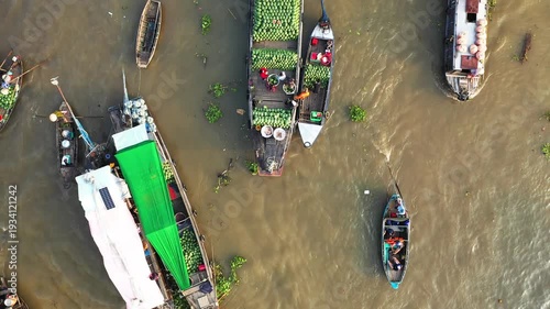 Aerial view of boats loaded with produce at the Cai Rang floating market on a river in Vietnam. Traditional wooden boats and fresh fruits are visible on the water.