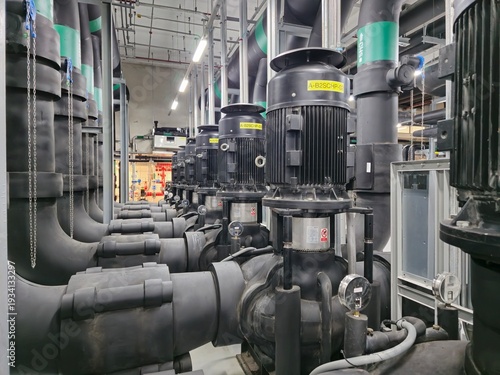 A series of black pipes with a yellow label on the top. The pipes are connected to a large machine