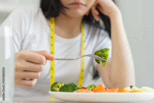 Tableau sur toile unhappy asian women is on dieting time looking at broccoli on the fork