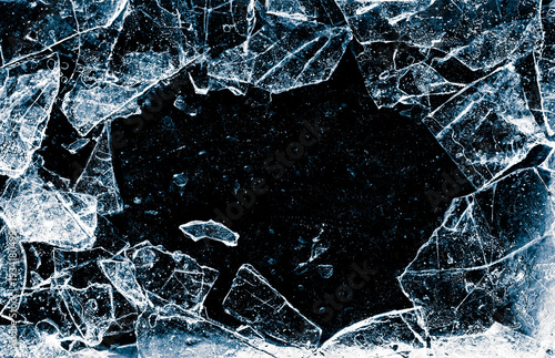Broken thin ice shards with space for copy. Crushed natural textured ice on a black background, close-up.