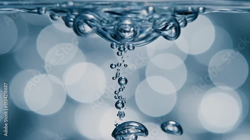 Closeup macro shot of air bubbles rising and merging in clear water with a soft bokeh background creating a mesmerizing abstract effect.