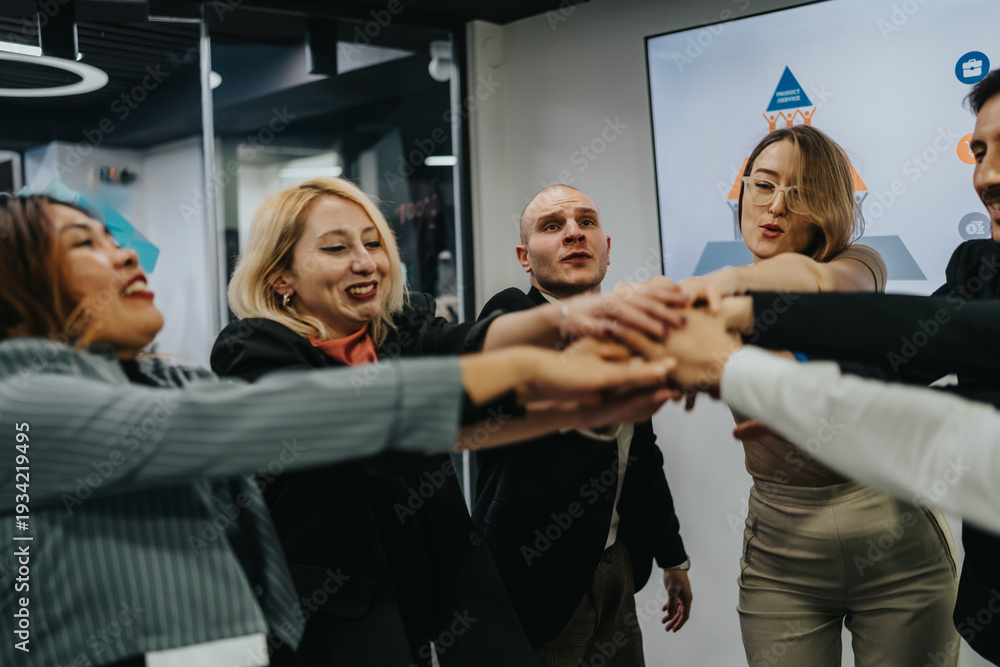 Fototapeta premium Diverse coworkers in business attire place hands together in a circle, symbolizing teamwork.