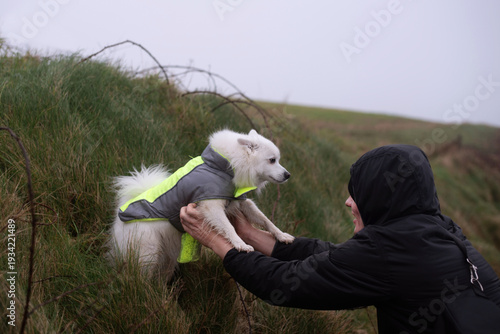Bild auf Leinwand A young man rescues his dog, who got lost during a walk in the mountains, dog an