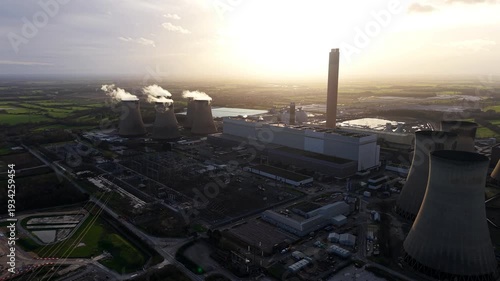 Aerial drone view of a massive power station near Selby, UK, featuring cooling towers billowing steam in the soft light of the golden hour.