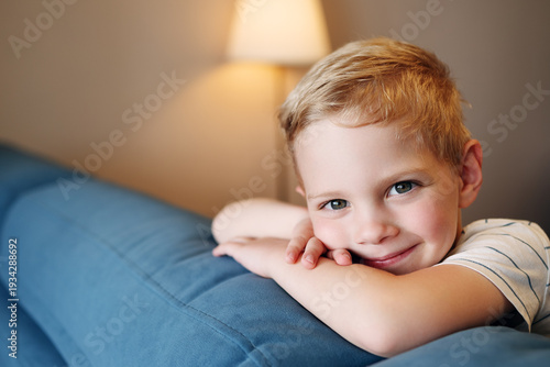 Foto A beautiful close-up portrait of a happy little boy leaning on a sofa and smiling