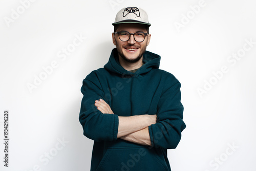 Young smiling man with crossed arms looking at camera on white background.