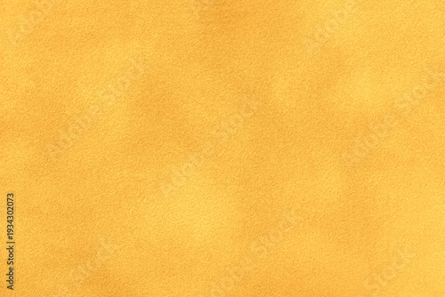 Yellow suede fabric background with matte nap velvet texture. Golden tones and soft felt textile surface in macro