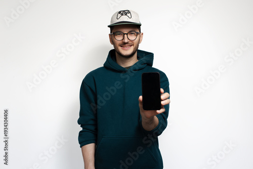 Smiling young man showing smartphone isolated on white background.