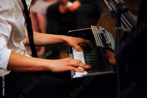 Close-up of a musician's hands playing a grand piano during a performance