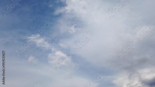 Cinematic time-lapse of fast-moving clouds over a vibrant blue sky. Dramatic cloudscape movement during a bright sunny day.