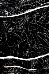 Bold black and white study of cracked ice displays a maze of thin bright lines and specks with strong diagonal bands a graphic winter abstraction that hints at maps roads and distant skylines