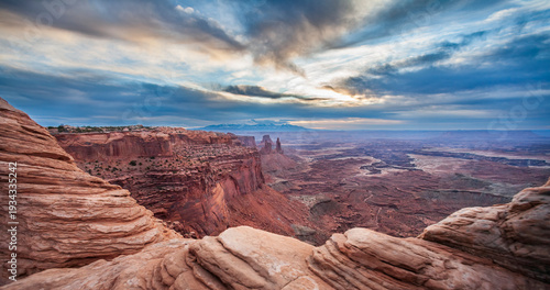 Panoramic sunrise over Canyonlands National Park with majestic red rock cliffs and dramatic cloudy sky, Utah, USA.
