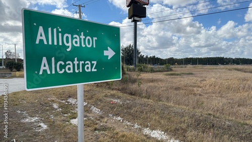 Bild auf Leinwand A green sign points to Alligator and Alcatraz on the side of a road during the d