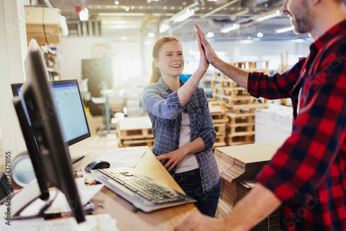 Smiling coworkers high five in warehouse office