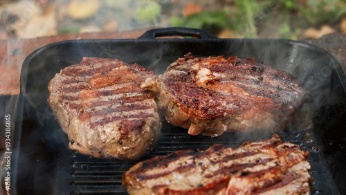 Εκτύπωση καμβά Three juicy steaks sizzling on a cast iron grill pan with visible steam rising