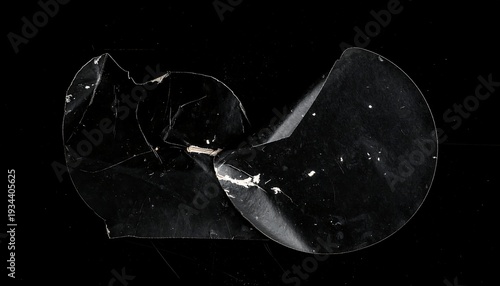 Black background showcases torn, semi-transparent plastic sheet, folded over itself. The sheet has cracks and imperfections