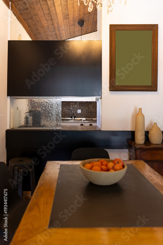 Detail of the living room with the dining room connecting to the kitchen, featuring a wooden table and modern chairs. Interior of a mountain chalet.
