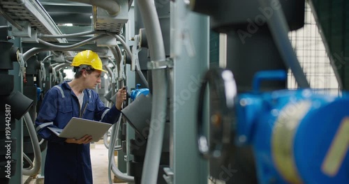 Professional industrial technician is inspecting pipeline valves with a laptop in a modern mechanical plant, focusing on digital transformation and operational efficiency.