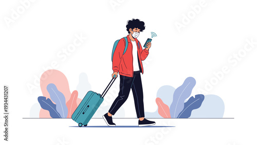 Young man wearing a face mask walks with a blue suitcase while checking his smartphone at an airport or train station.