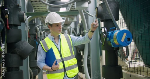 Professional engineer is inspecting industrial machinery valves in a modern plant, focusing on operational efficiency, quality control, and industrial safety compliance.