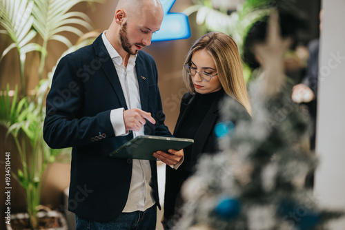 Quadro em tela Two professionals review information on a tablet in a modern office
