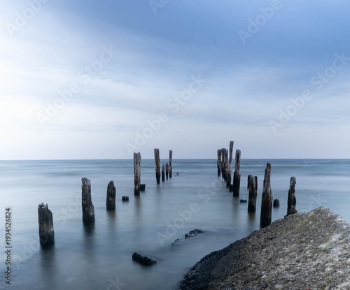 Cuadro en lienzo Old wooden pier posts disappearing into the Baltic Sea, Latvia