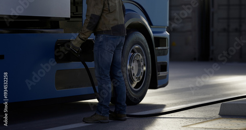 Foto Driver connecting a charging cable to an electric semi truck