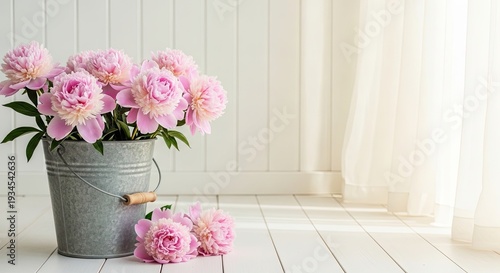 Pink peonies in a metal bucket on a white wooden floor