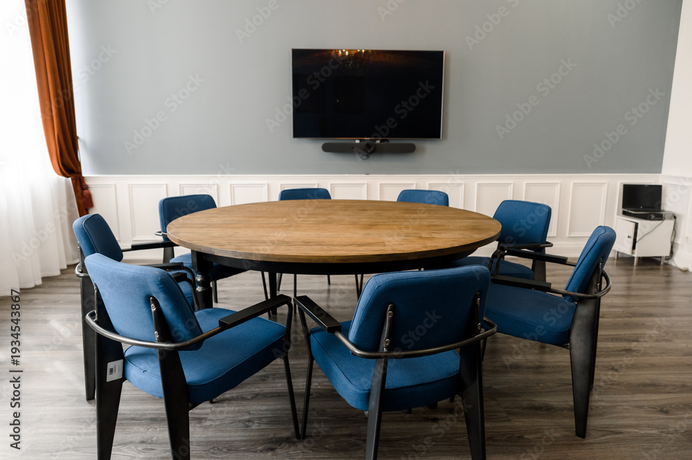 Fototapeta premium Round wooden table with blue chairs in modern office