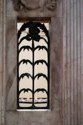 elaborate lattice work in the gothic window inside Oude Kerk in Amsterdam with some candle light behind it