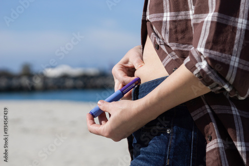 Konstfotografi close up of a slim woman injecting semaglutide medication into her stomach using an insulin pen